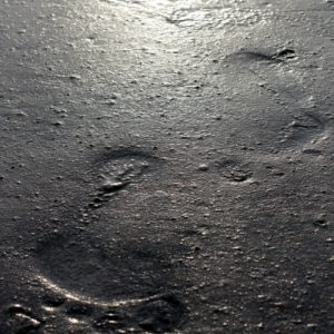 this shows foot prints in the sand depicting a lasting legacy